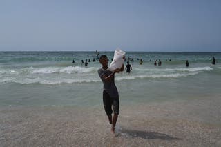 Palestinians collect aid that landed in the Mediterranean Sea after being airdropped over central Gaza, at the shore of Zawaida, Gaza Strip